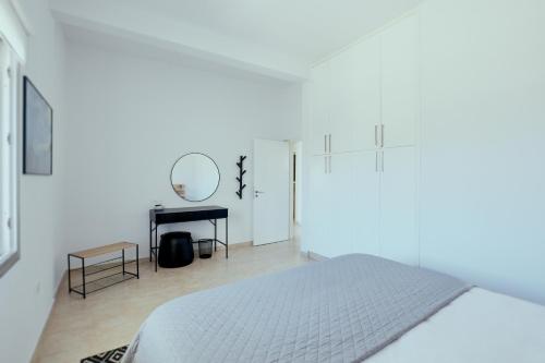 Un dormitorio blanco con una cama y un espejo. en Citrus & Sun Luxury Home, en Pafos