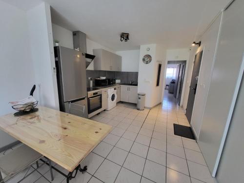 une cuisine avec une table en bois au milieu dans l'établissement Air conditioned appartment 270m from beach, à Saint-Raphaël