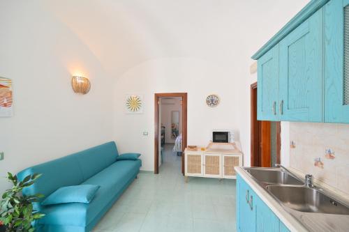 a living room with a blue couch and a sink at Chiaia Di Rose Seaside Suite in Sant'Angelo D'Ischia