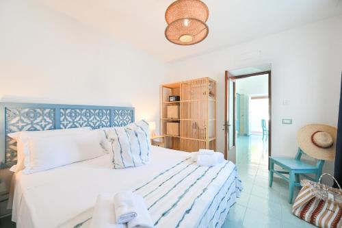 a bedroom with a white bed with a blue headboard at Chiaia Di Rose Seaside Suite in Sant'Angelo D'Ischia