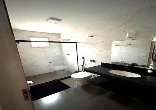 een badkamer met een toilet, een wastafel en een spiegel bij Cobertura - Praia do Morro in Guarapari