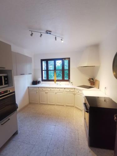 a kitchen with white cabinets and a window at Les Mûriers in La Ciotat