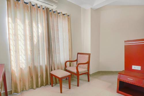 a living room with a chair and a television at Collection O 29 Church's Inn Near Cubbon Park in Bengaluru
