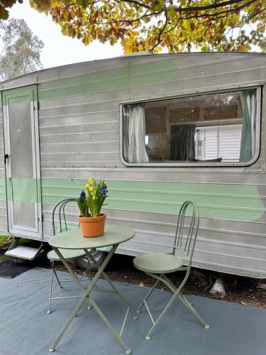 a table and two chairs next to a trailer at Castlemaine Gardens Vintage 60's Caravan in Castlemaine