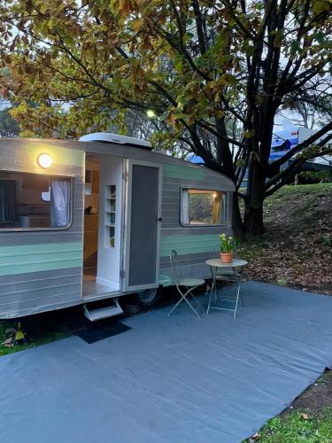 une caravane verte et blanche garée à côté d'une table dans l'établissement Castlemaine Gardens Vintage 60's Caravan, à Castlemaine