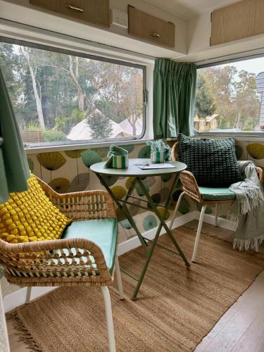 a living room with a table and chairs and a window at Castlemaine Gardens Vintage 60's Caravan in Castlemaine