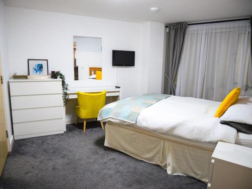 ニューキーにあるModern surf pad, steps from Towan beachのベッドルーム1室(ベッド1台、デスク、黄色い椅子付)