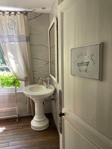 a bathroom with a white sink and a mirror at L'Écrin du Marquis 