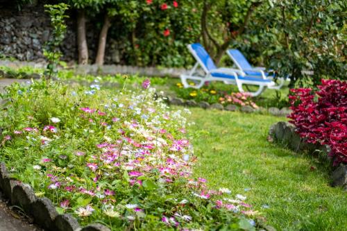 two blue chairs sitting in a garden with flowers at Quinta Sao Roque in São Roque