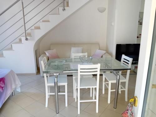 a dining room with a glass table and white chairs at L'Albero della vita in Piano di Sorrento