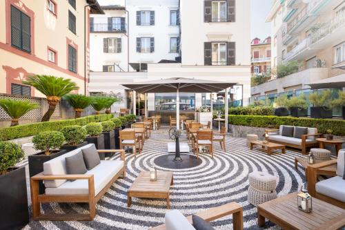 a patio with tables and chairs and an umbrella at LHP Hotel Santa Margherita Palace & SPA in Santa Margherita Ligure