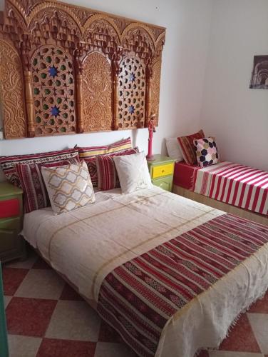 a bedroom with a bed with a wooden headboard at Riad dar MUMTI in Saidia 