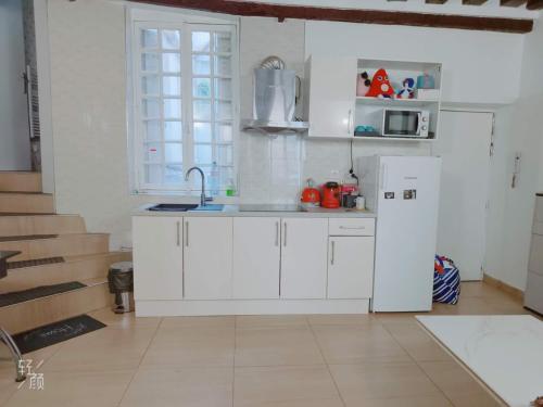une cuisine avec des armoires blanches et un réfrigérateur blanc dans l'établissement 休闲民宿, à Paris