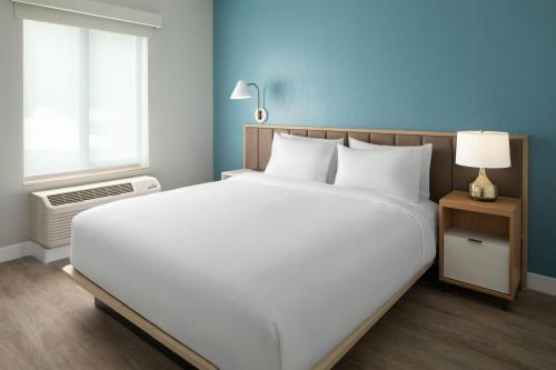 a large white bed in a room with a window at TownePlace Suites Wilmington Wrightsville Beach in Wilmington