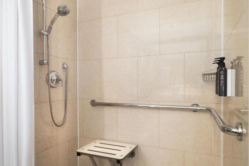 a bathroom with a shower with a bench in it at Sheraton Cavalier Calgary Hotel in Calgary