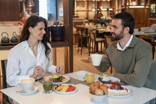 a man and a woman sitting at a table with food at AC Hotel by Marriott Lima Miraflores in Lima