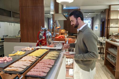 a man standing in front of a buffet of food at AC Hotel by Marriott Lima Miraflores in Lima