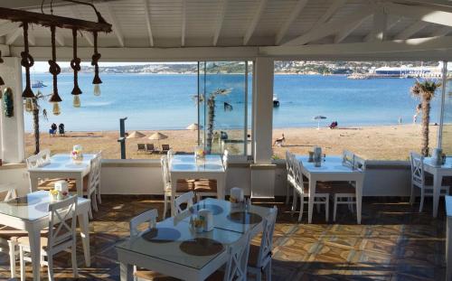 a restaurant with tables and a view of the beach at Alesya Otel in Çiftlikköyü