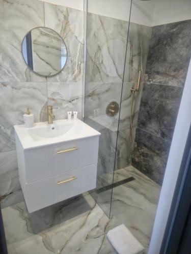 a bathroom with a sink and a shower with a mirror at White Residence in Oradea