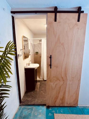 a bathroom with a wooden door and a sink at The Mermaid and The Pearl Boutique Hotel in Isla Mujeres