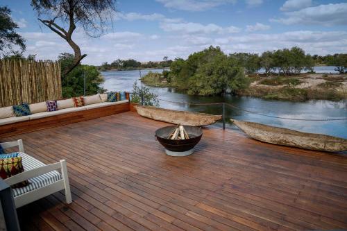 a wooden deck with two benches and a river at Zambezi Dusk in Livingstone