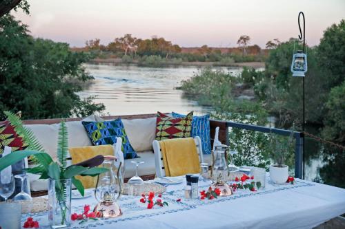 a table with a couch and a view of a river at Zambezi Dusk in Livingstone