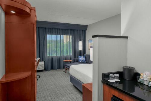 a hotel room with a bed and a chair and a desk at Courtyard Pittsburgh Settlers Ridge/Robinson Township in Robinson Township