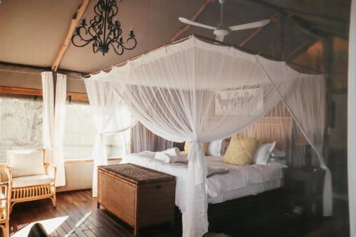 a bedroom with a canopy bed with white curtains at Zambezi Dusk in Livingstone