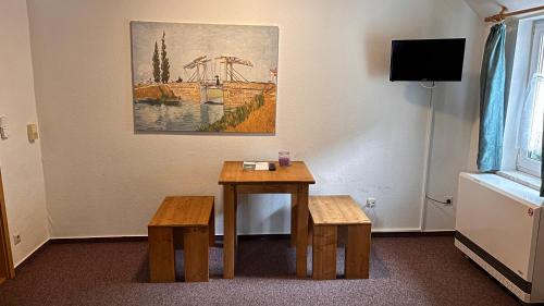 a room with a table and two benches and a painting at Hostel Ziegenrück in Ziegenrück