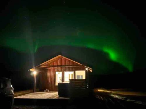 a cabin with the green northern lights in the sky at Secret Cabin Hvítárdalur in Fludir