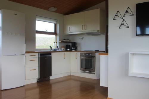 a kitchen with white cabinets and a black refrigerator at Secret Cabin Hvítárdalur in Fludir