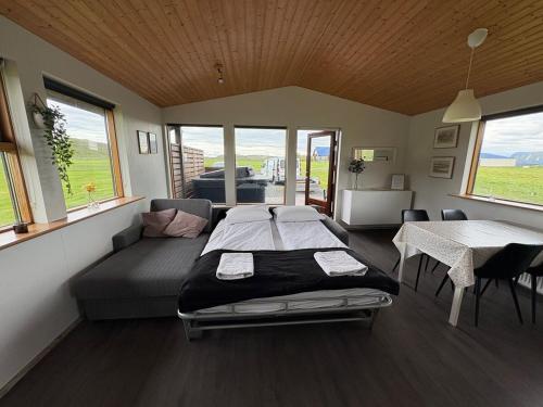 a bedroom with a bed and a table and windows at Secret Cabin Hvítárdalur in Fludir