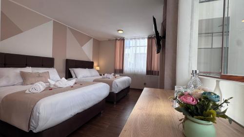 a hotel room with two beds and a vase of flowers at Andari Hoteles in Arequipa