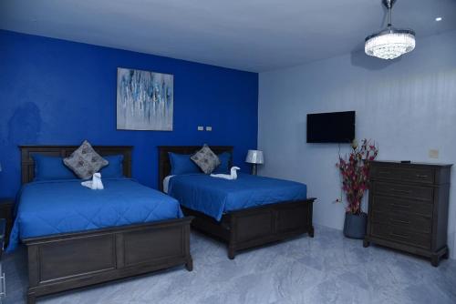 1 dormitorio azul con 2 camas y TV en LS Stonethrow - Sapphire Deluxe, en Montego Bay