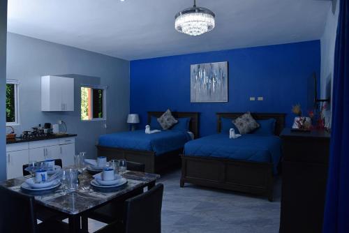 a blue room with two beds and a dining table at LS Stonethrow - Sapphire Deluxe in Montego Bay
