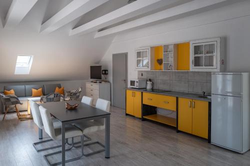 a kitchen and living room with a table and yellow cabinets at Apartmány Pelech in Trenčianske Teplice