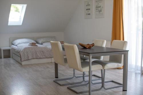 a dining room table with chairs and a bed at Apartmány Pelech in Trenčianske Teplice