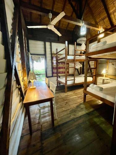 a room with bunk beds and a table in a room at La Perla Hostel and Cabins in Las Tunas