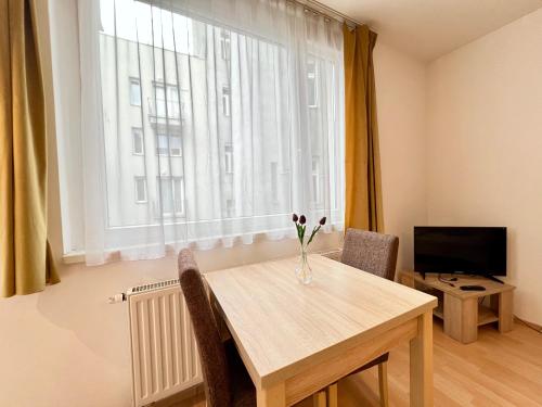 Una mesa de comedor con un jarrón de flores encima. en Budapest Citylink Aparthotel, en Budapest