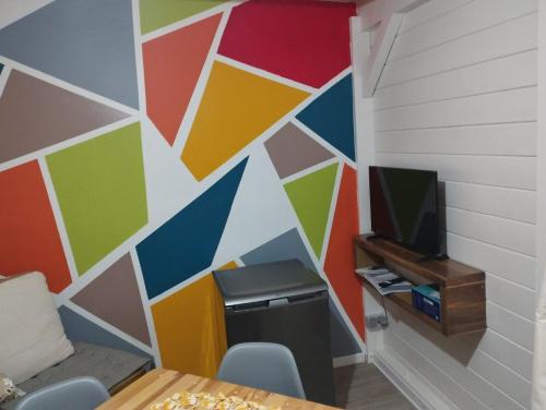 a room with a colorful wall with a tv at Ti Kaz an nou in Grand-Bourg