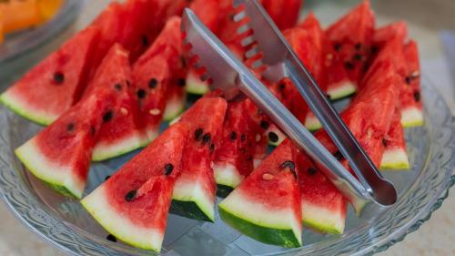 a glass bowl filled with watermelon slices with two forks at Hotel do Sol Executive in São Sebastião