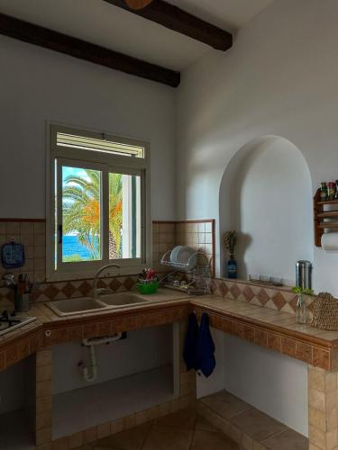 a kitchen with a sink and a window at La Finestra Sul Mare in Tusa