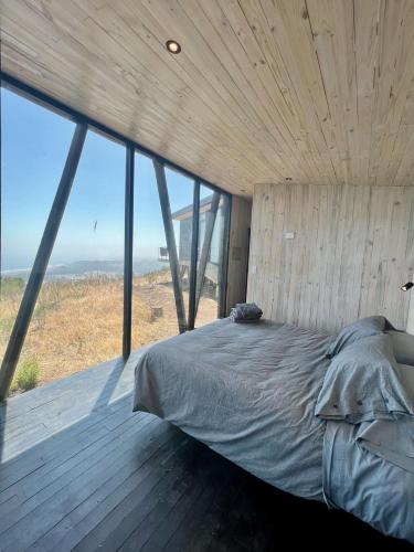a bedroom with a bed in a room with windows at Casa Quebrada Olas de Buchupureo in Cobquecura