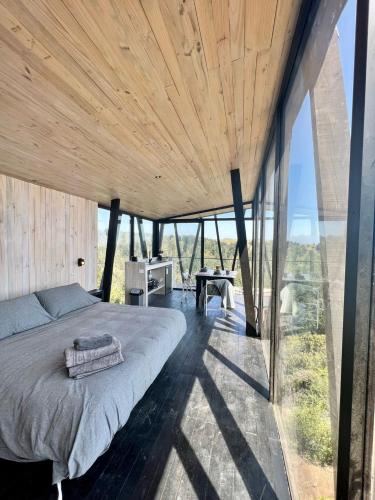 a bedroom with a bed and large glass windows at Casa Quebrada Olas de Buchupureo in Cobquecura