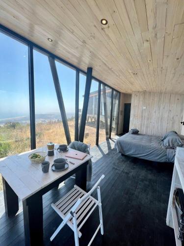 a room with a table and a bed and some windows at Casa Quebrada Olas de Buchupureo in Cobquecura