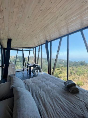 a bedroom with a large bed in front of a window at Casa Quebrada Olas de Buchupureo in Cobquecura