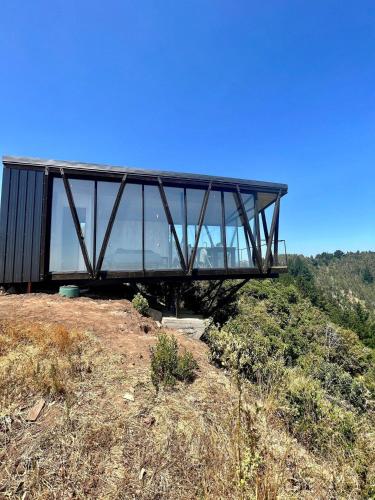 a glass building on top of a hill at Casa Quebrada Olas de Buchupureo in Cobquecura