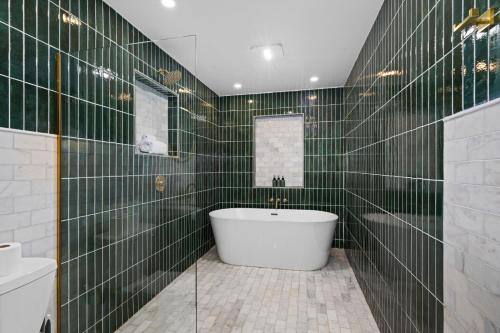 a bathroom with green tiled walls and a bath tub at Historic Cotton Mansion by Heirloom Boutique Collection in Duluth