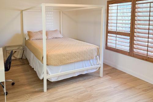 a bedroom with a four poster bed and a window at Tranquil Tierra in Palm Springs