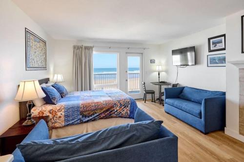 a bedroom with a bed and a blue couch at Ground Floor Condo - Ocean View - Pool & Hot Tub in Lincoln City